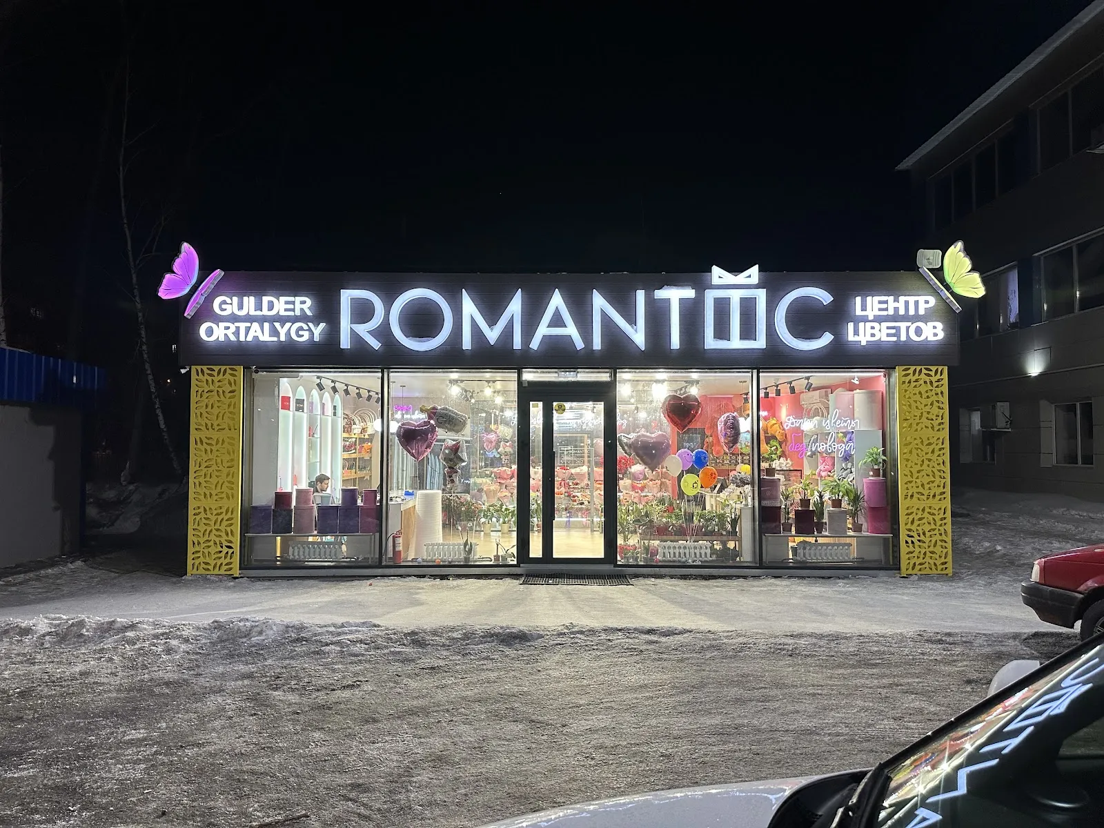 Световая вывеска «Romantic. Центр цветов» вечером